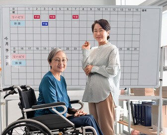 ホワイトボードで予定を管理している介護施設スタッフと利用者