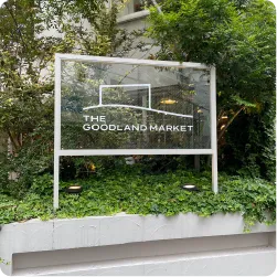 植栽の中に設置された透明パネルの自立式看板