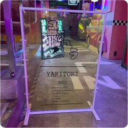 透明のシートへ店名を印字した焼き鳥店の自立看板