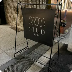 黒地に白い細身の文字で店名をあしらった眉毛サロンのスタンド看板