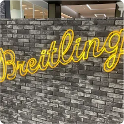 レンガ調の壁面に設置された黄色の筆記体のネオンサイン