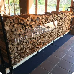 積み上げた薪に、白い立体文字を配置した透明プレートを設置したホテル看板