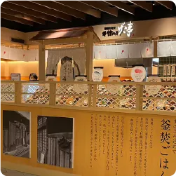 木目調の仕切り壁に飲食店の紹介文を掲示したサイン