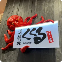 赤いタコの立体装飾をつけたタコ焼き屋の壁面サイン