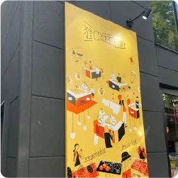 楽し気に飲食する人々のイラストが描かれた飲食店街の黄色いプレート看板