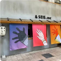 カラフルな手のイラストが並ぶアーティスティックな暖簾