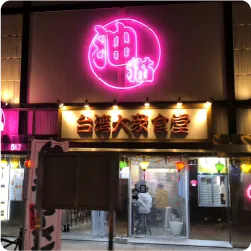 ピンク色のネオンサインが光る台湾料理店の看板